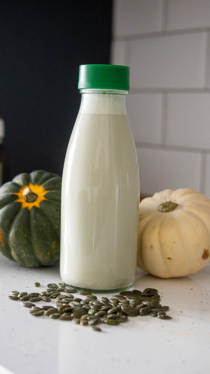 Bottle with homemade pumpkin seeds, next to small pumpkins 