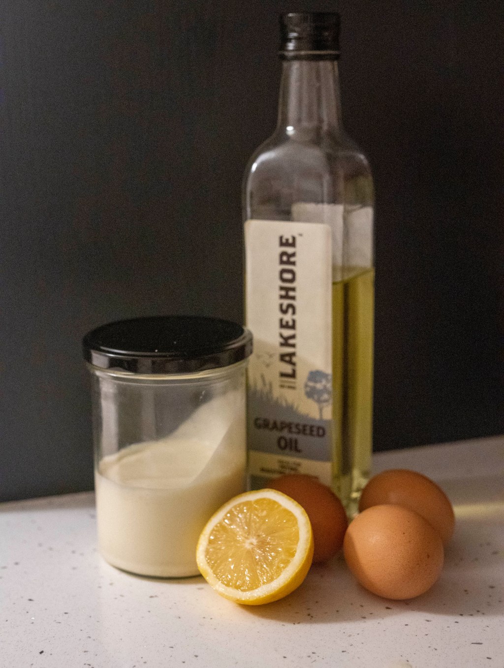 Photo of Glass bottle of Grapeseed's Oil, 3 eggs, and half of a lemon and a Jar with homemade mayo