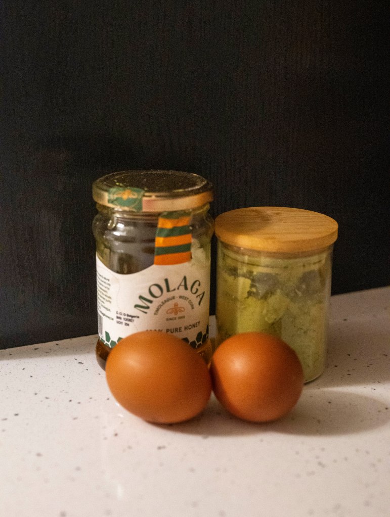 Photo of a glass jar with honey, glass jar with matcha and two eggs